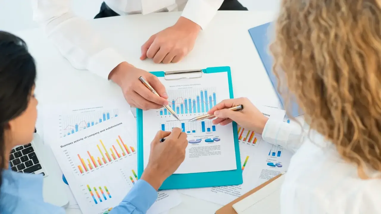 Três pessoas conversando sobre uma planilha de gastos de investimentos